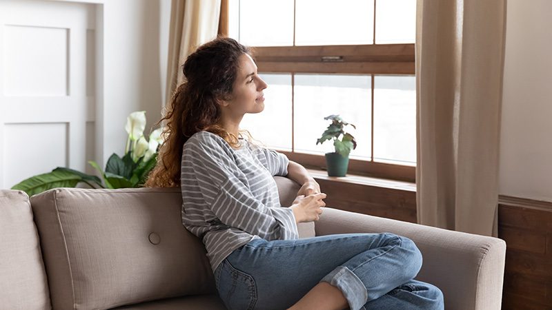 A woman sits on a couch in a sober living home.