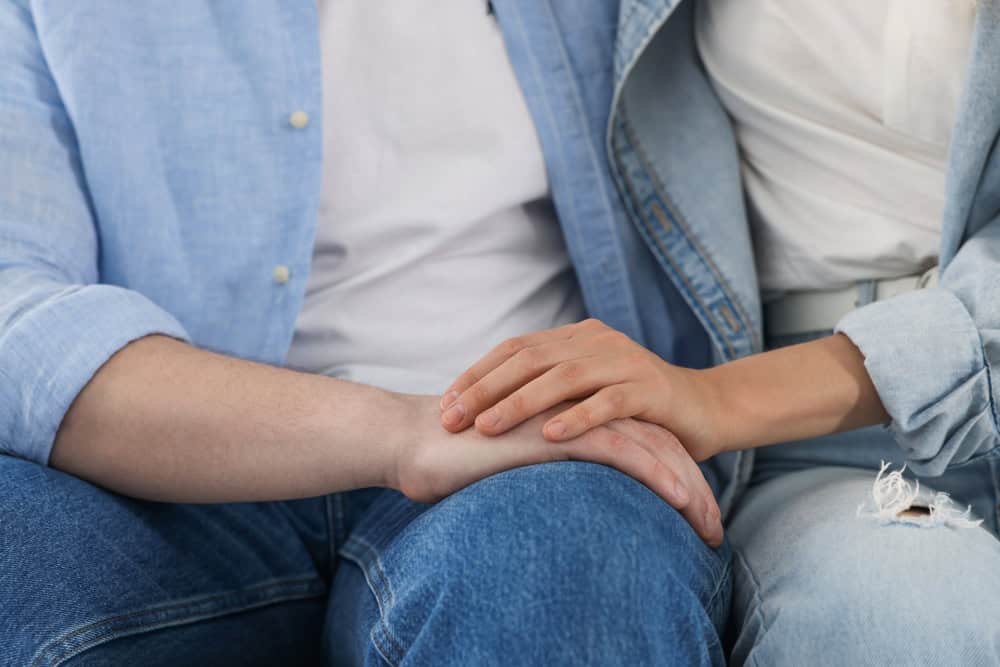 Husband and wife holding hands after asking the question am I abandoning or enabling my spouse.