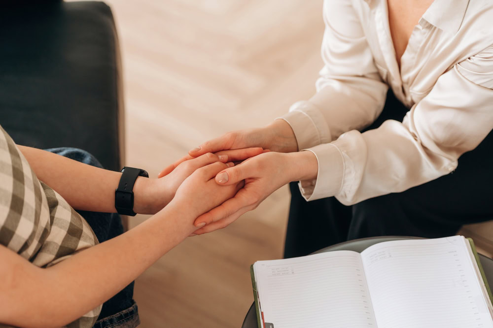 Therapist holding the hands of a child after talking about how to overcome childhood trauma.