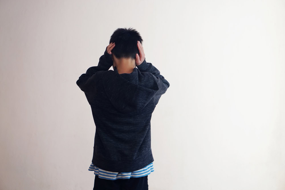 Child covering ears while thinking about how to overcome childhood trauma.