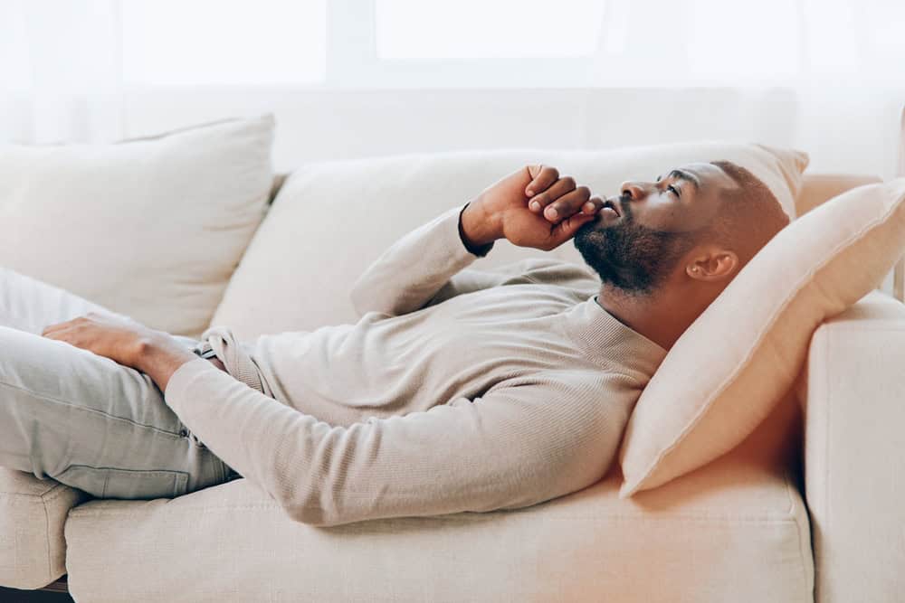 Man laying down on a couch, thinking about emotional reasoning cognitive distortion.